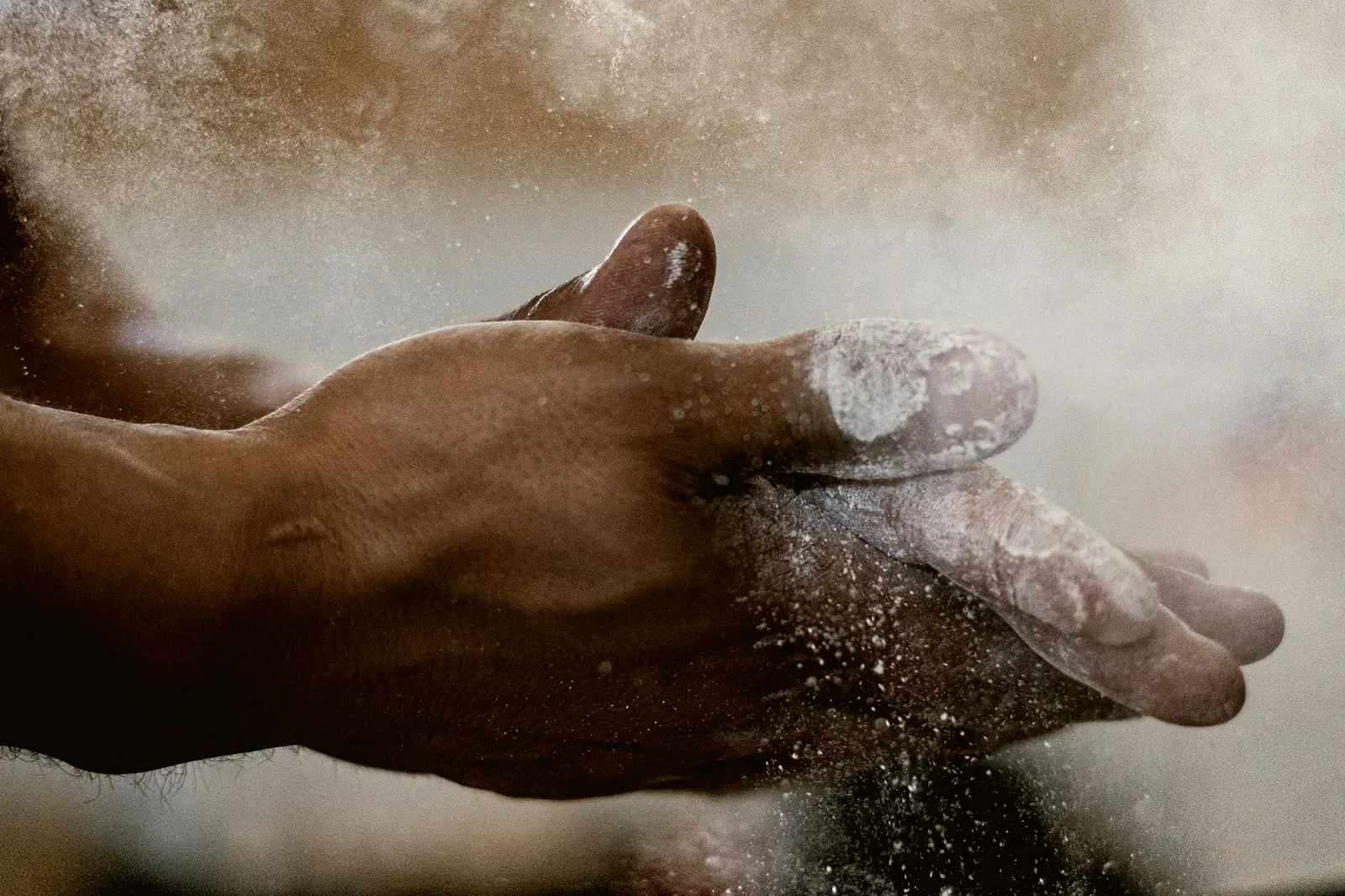 Chalk-covered hands, with chalk dust in the air