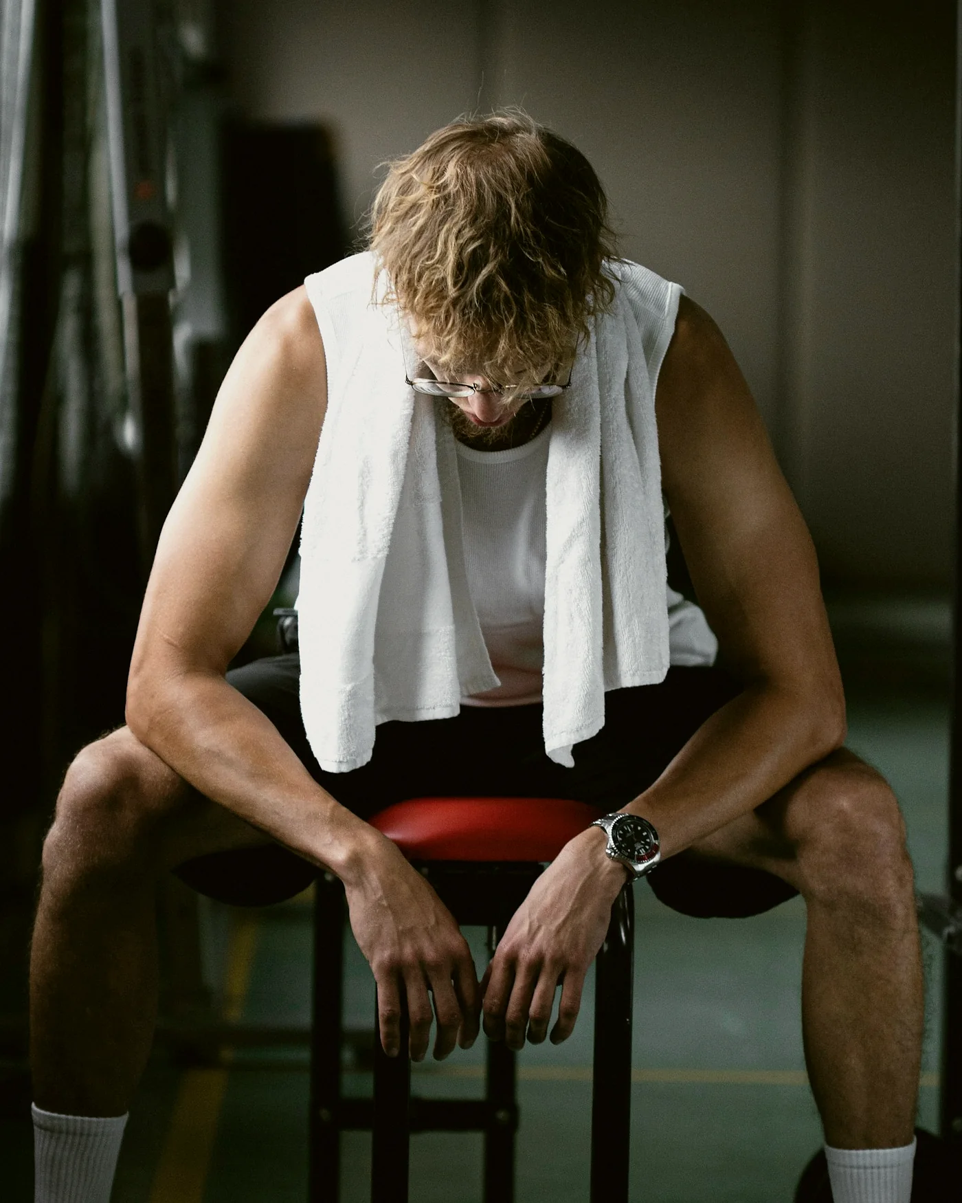 Someone sitting between sets, a towel over the shoulders and head bowed