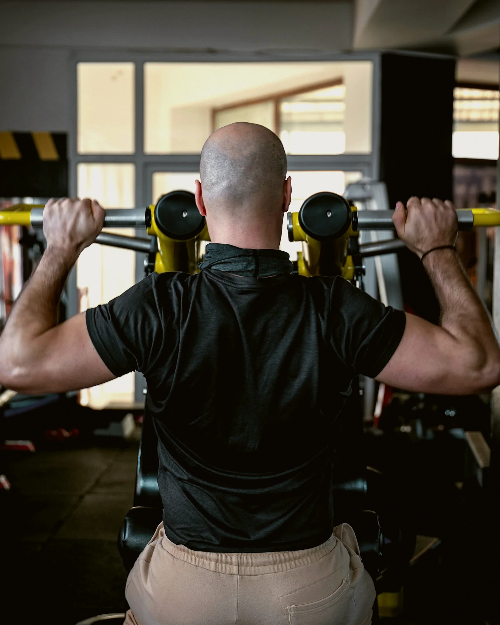 A man seen from behind doing a seated shoulder press